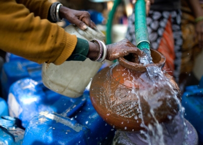 Indian residents fill water buckets at a delivery from a municipal tanker.