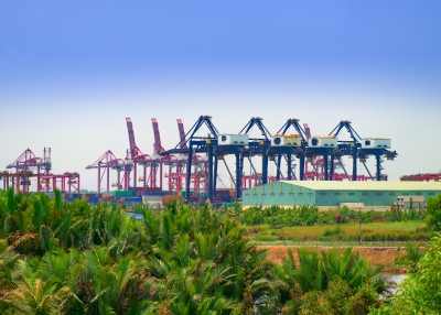Logistics and transportation of Container Cargo with working crane bridge in shipyard at sunrise
