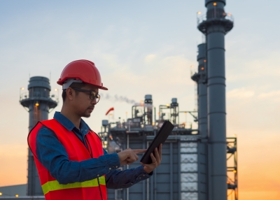 Service engineer is working with laptop in power plant at twilight