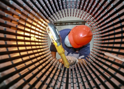 A worker checks a rotor core used for wind turbines