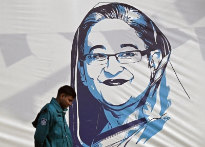  policeman walks past a portrait of Bangladesh's Prime Minister Sheikh Hasina, in Dhaka on January 8, 2024. Hasina won re-election for a fifth term on January 7, officials said, following a boycott led by an opposition party she branded a "terrorist organisation".