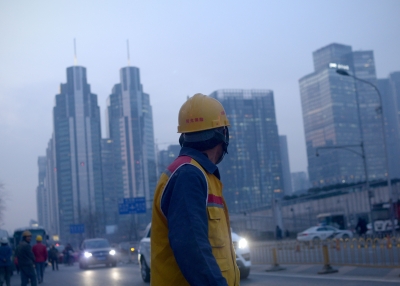 Chinese worker looking on as he walks along a street after work in Beijing.