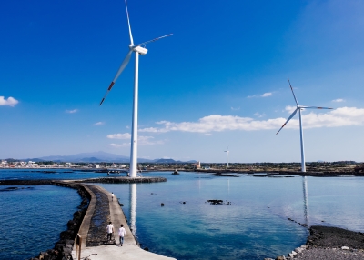 People walking on a path connecting wind mills.