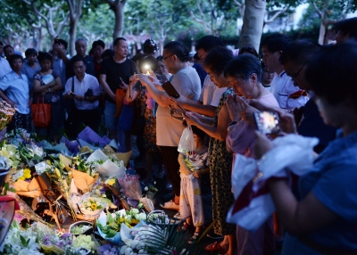 Children and adults pray during a candle-light vigil at the site of a knife attack which left two children dead in Shanghai on June 28, 2018.